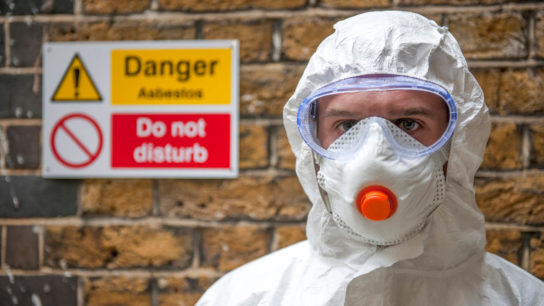 worker wearing protective clothing handles asbestos
