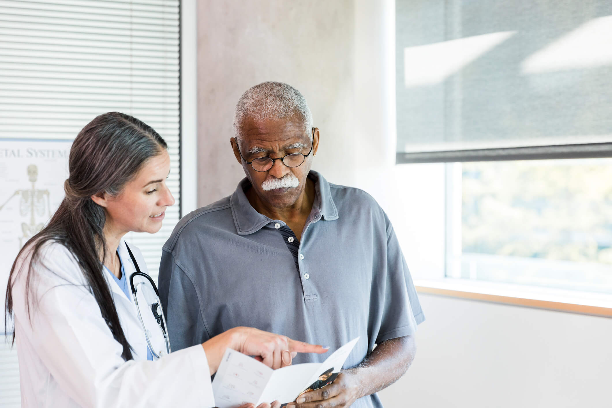 Black male patient looking at chart with doctor.