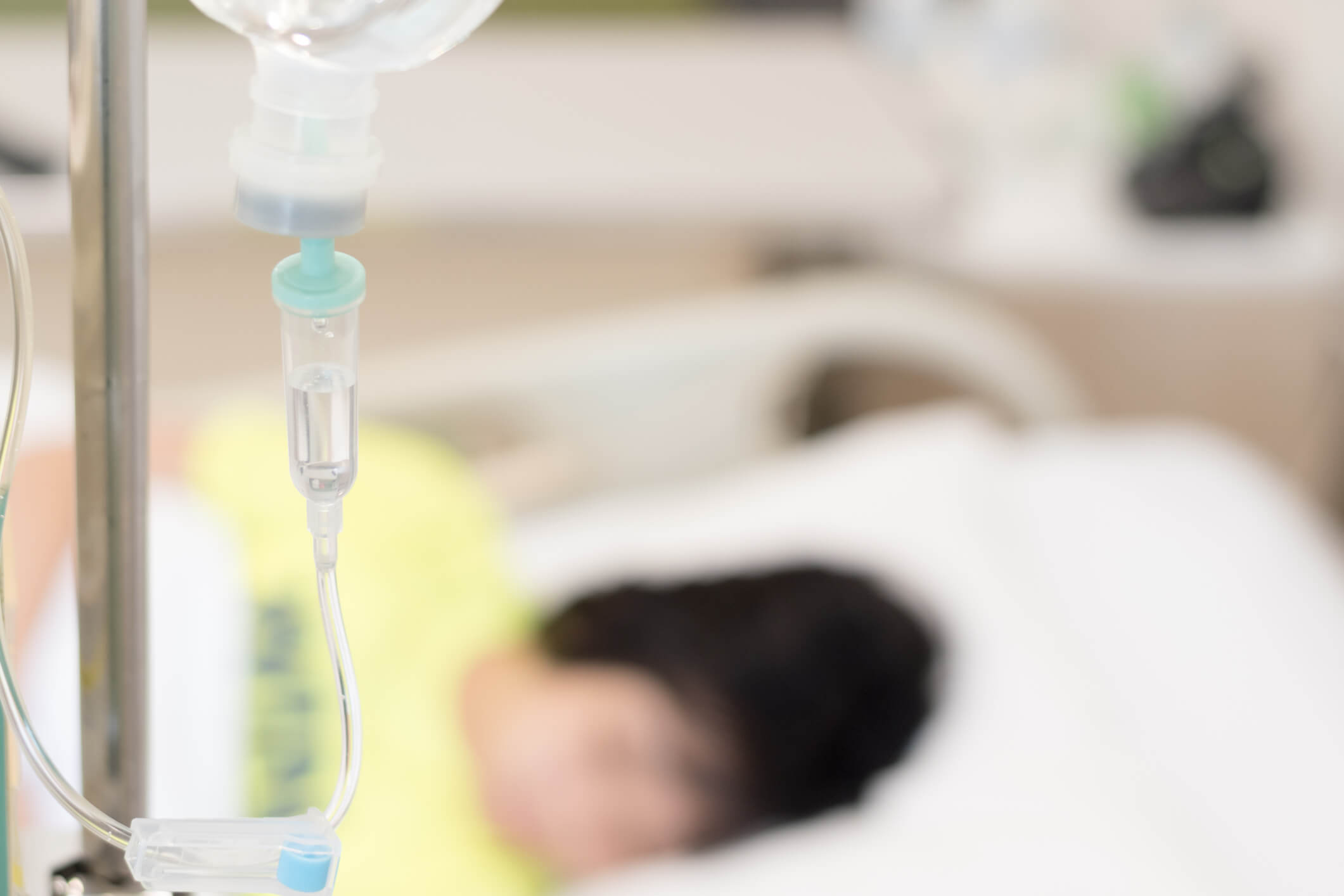 Child patient on hospital bed with IV drip.
