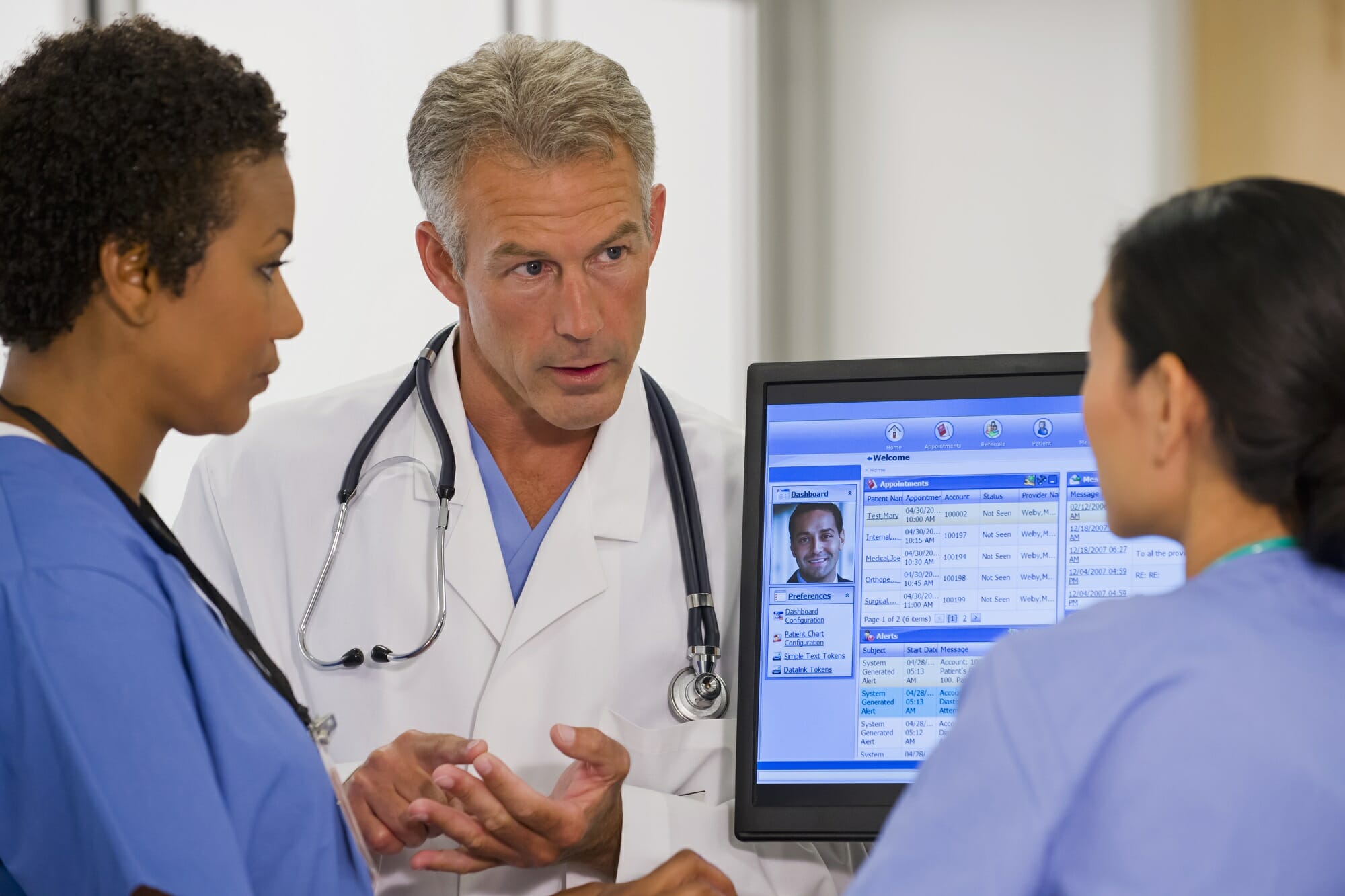 Clinicians talking with an electronic health record showing on the screen