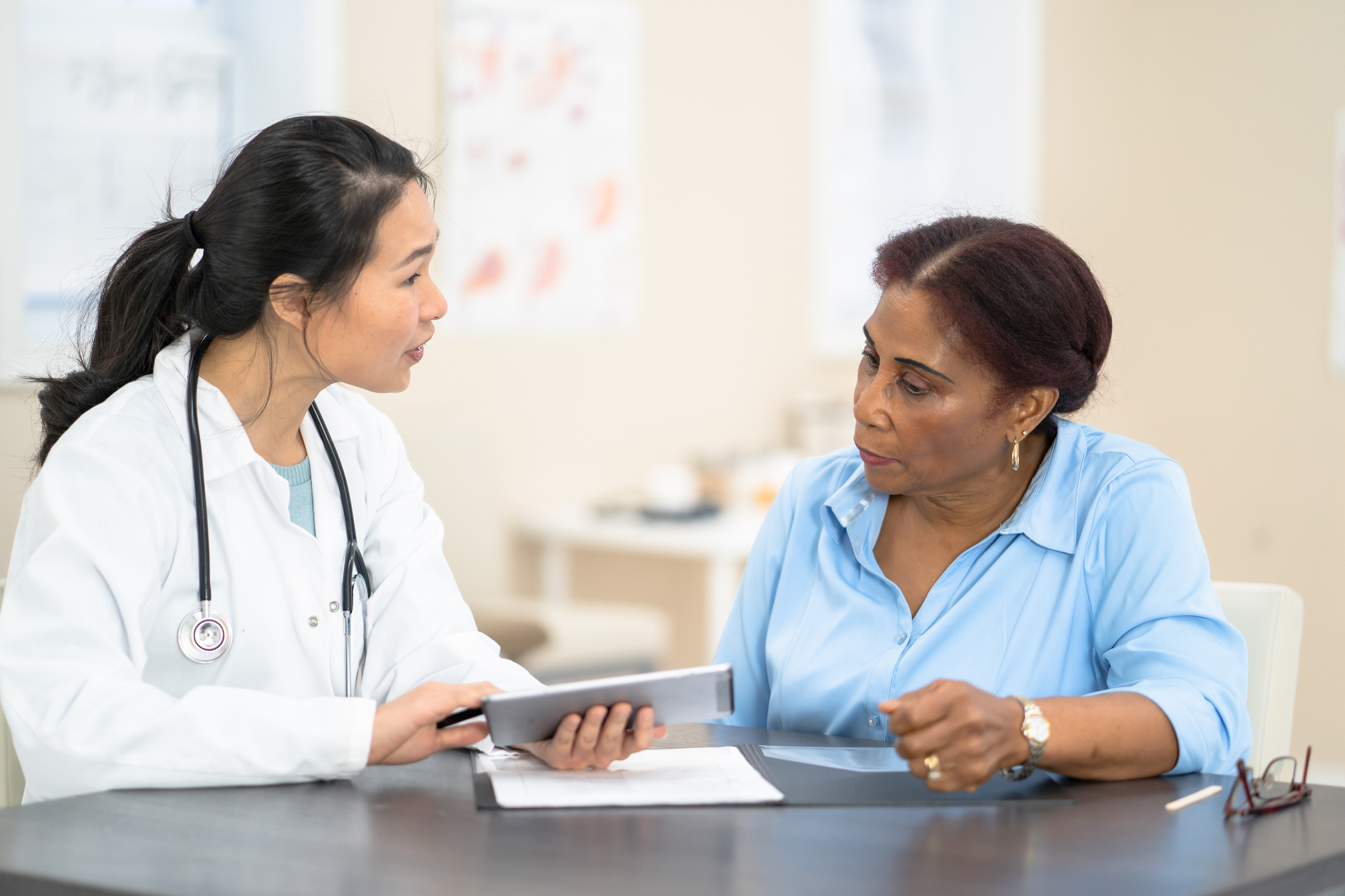 Older, black female patient and doctor review medical records