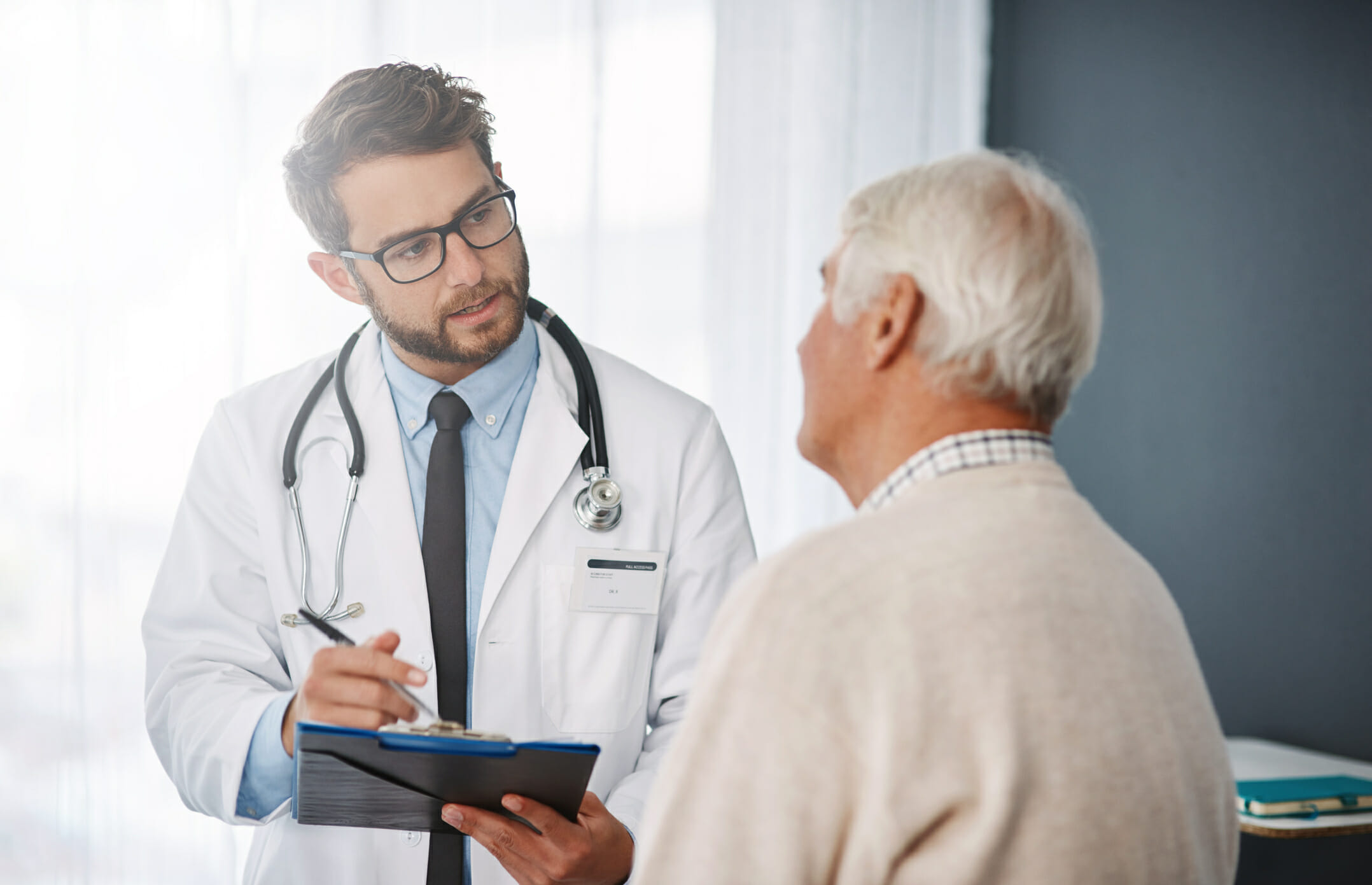 Shot of a young male doctor talking with older male patient