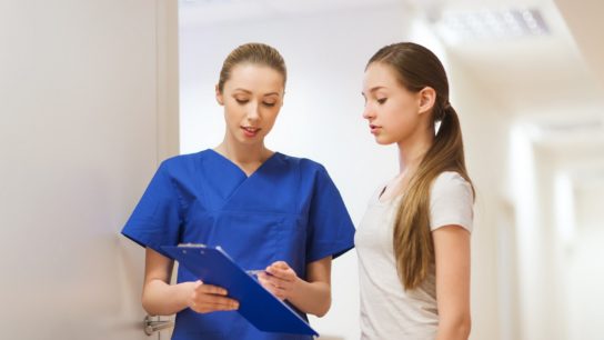 A nurse speaks with a female teen patient.