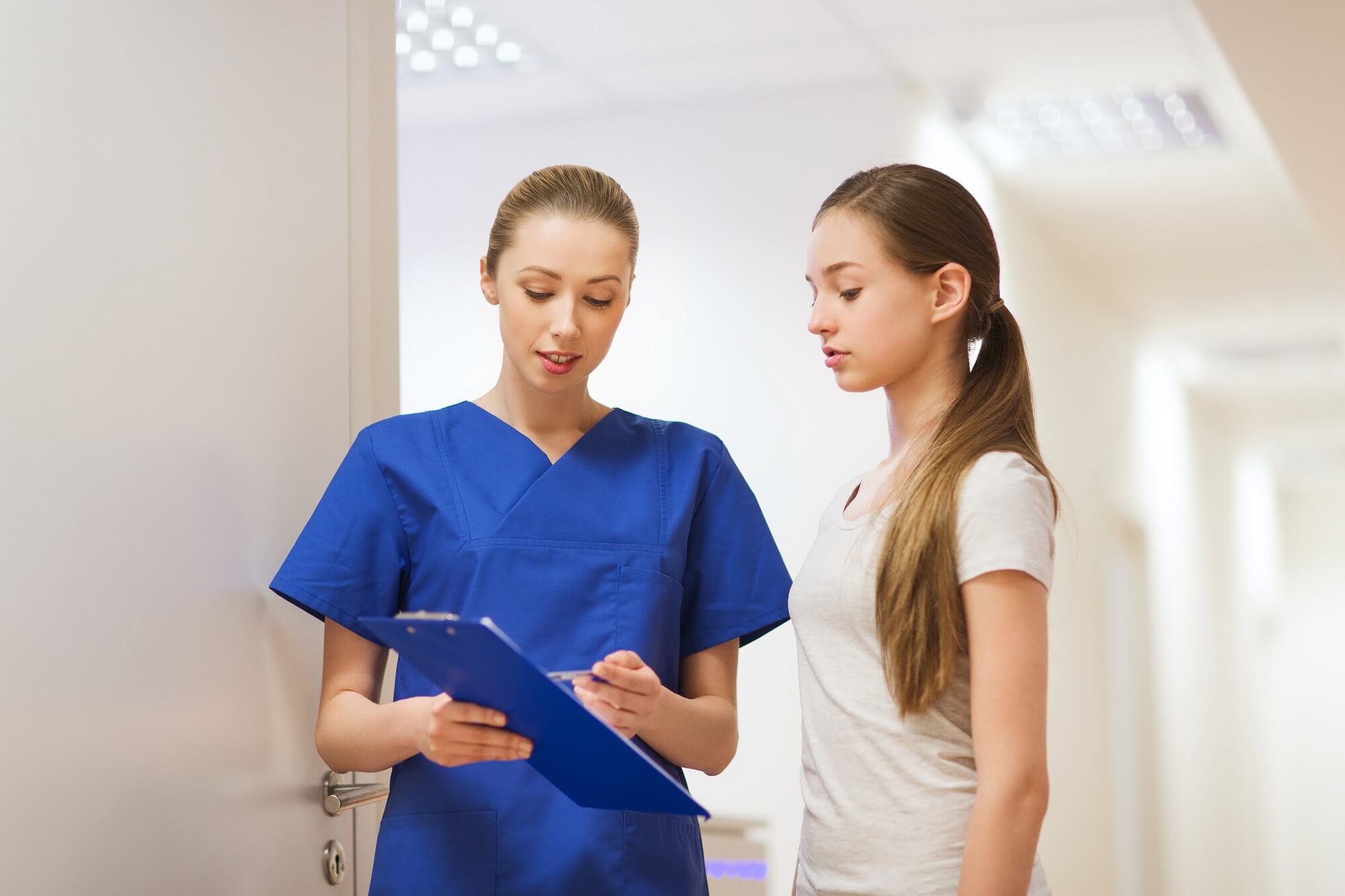 A nurse speaks with a female teen patient.