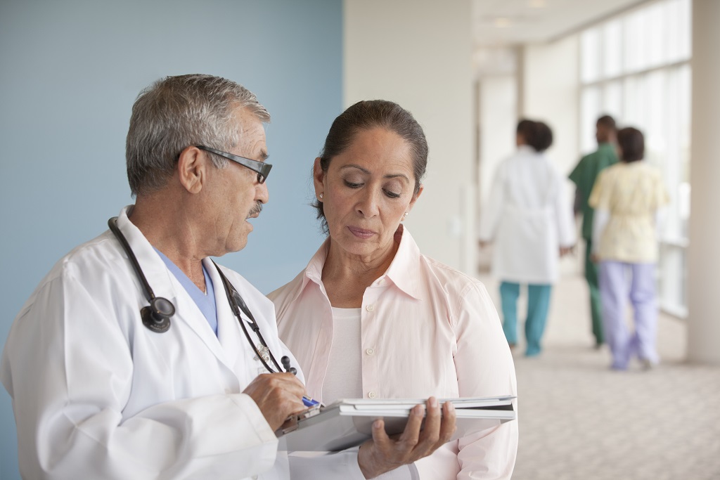 Male doctor explaining results to middlea-ged female patient in hallway