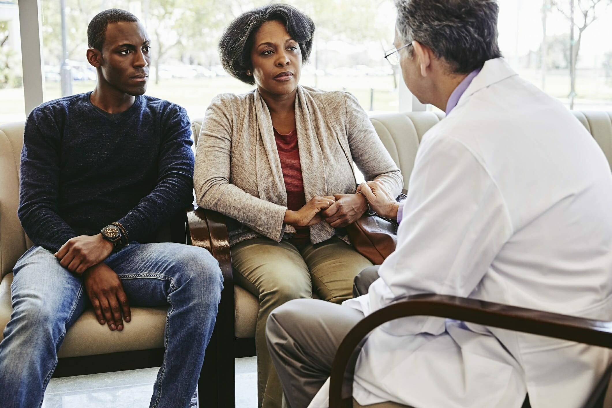 Doctor comforting mature woman sitting with adult son