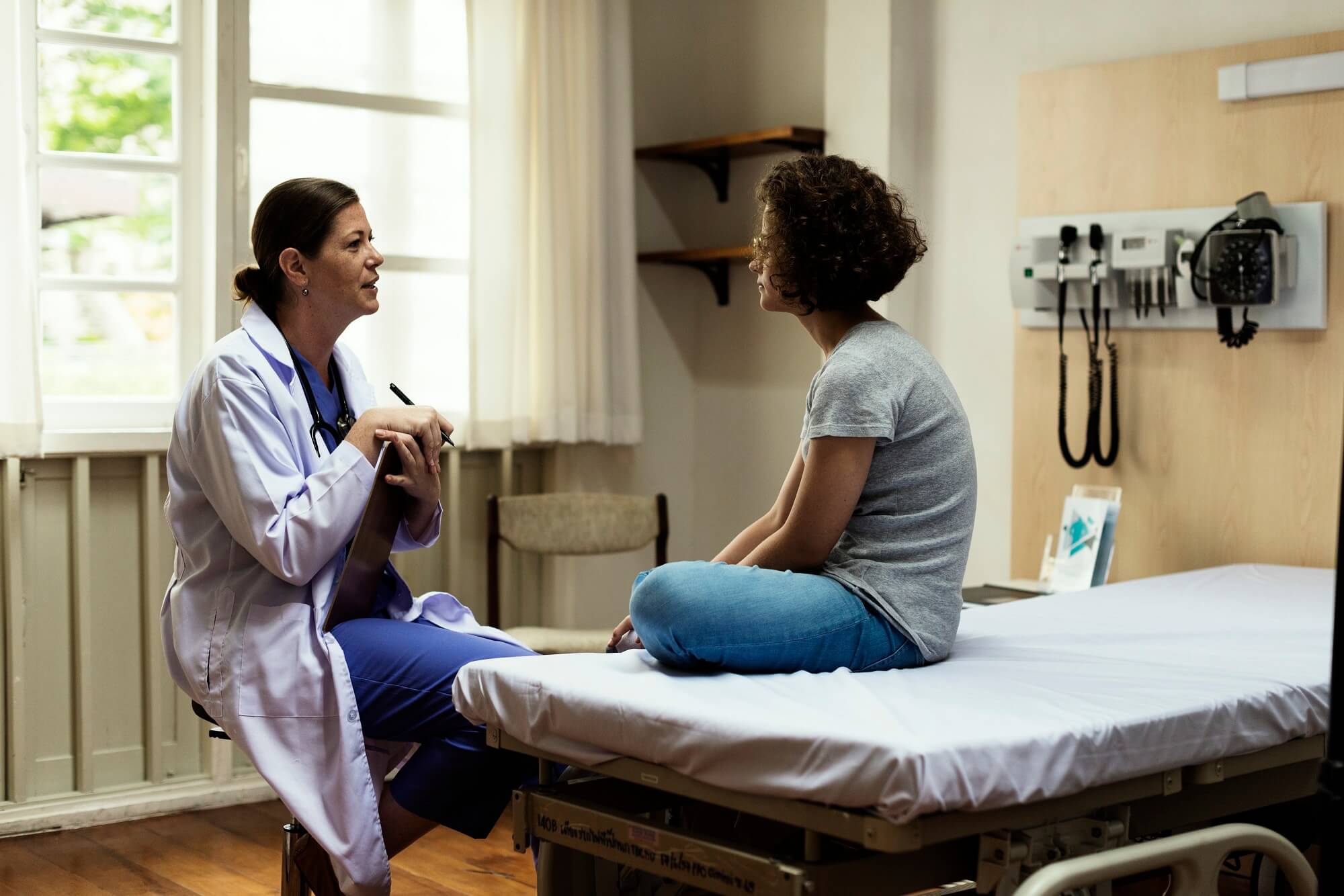 A doctor speaks with a female teenage patient.