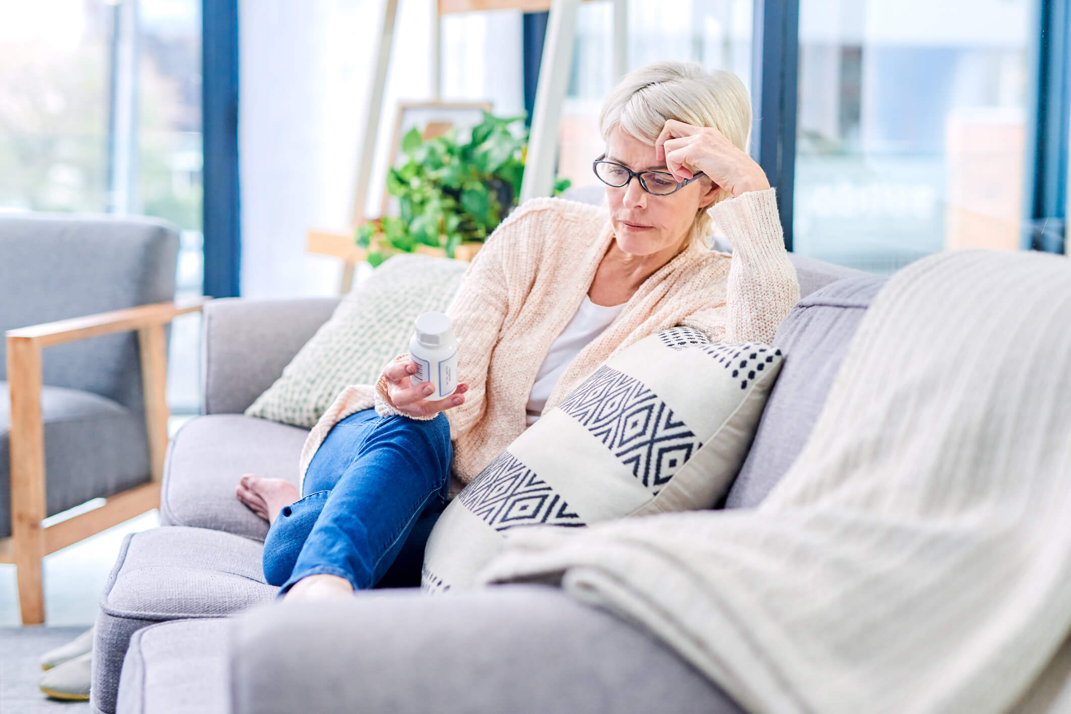 Older woman looking at bottle of pills.