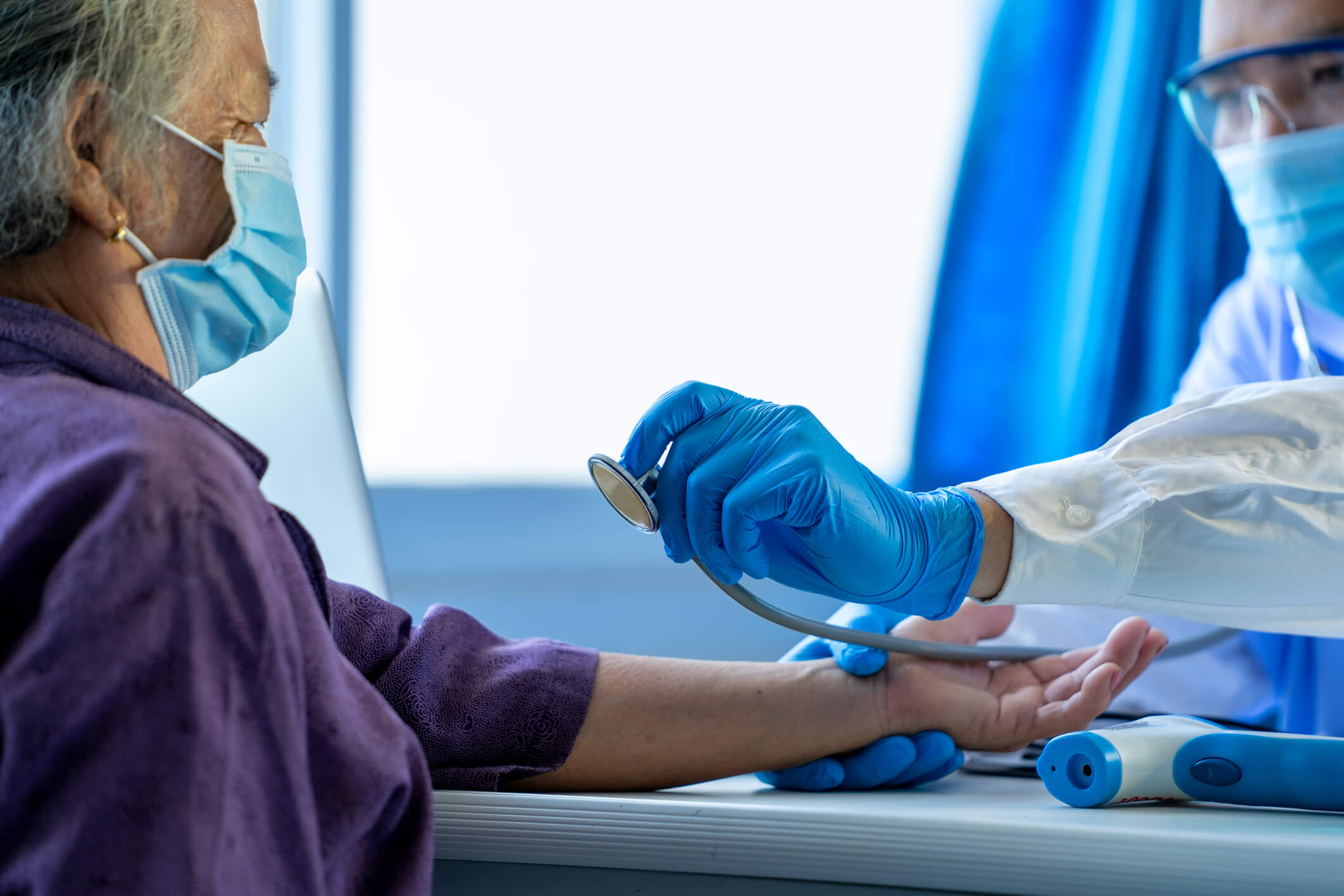 Doctor examines older female patient's heartrate.