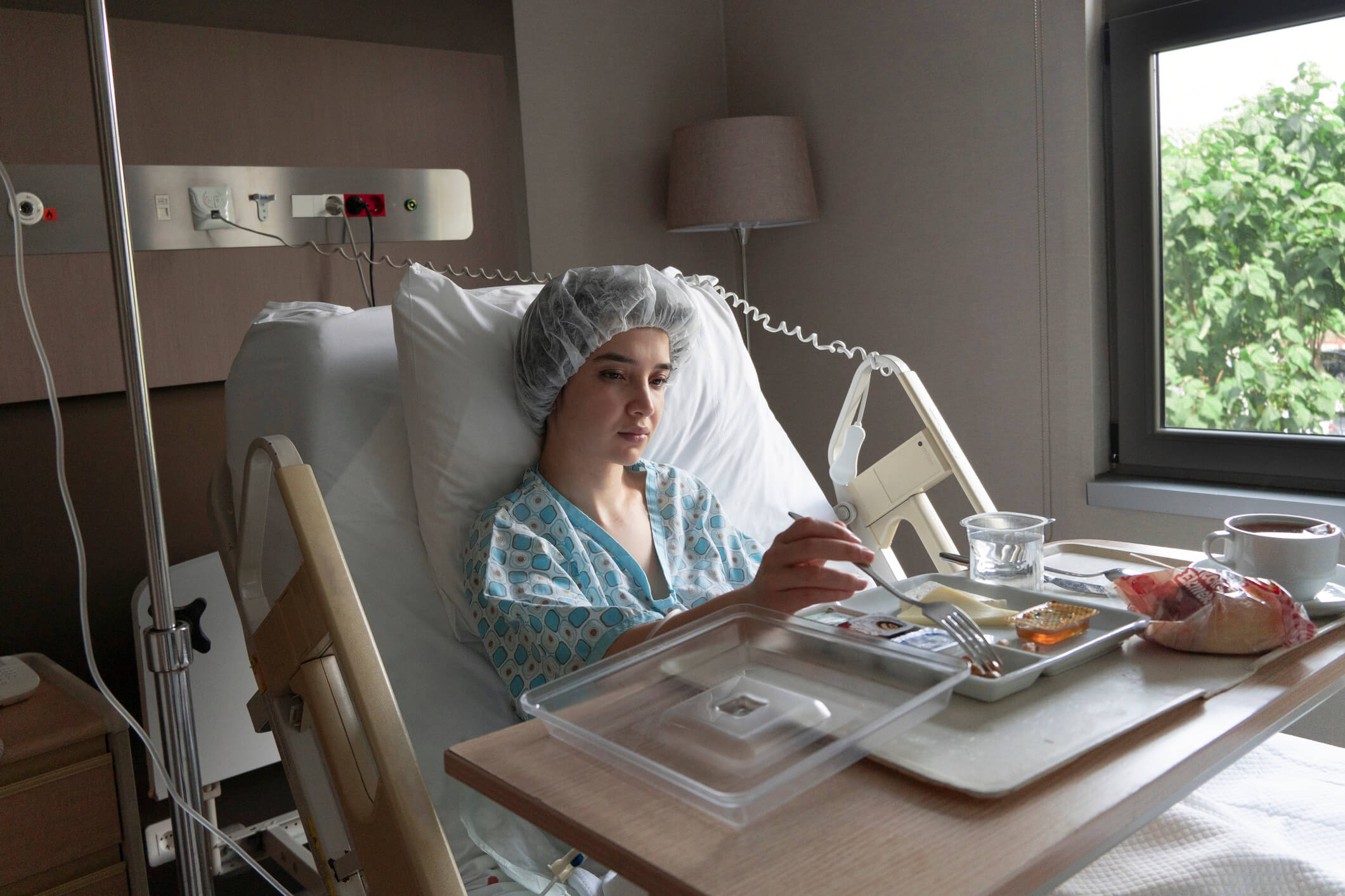 Young patient on hospital bed eating food.