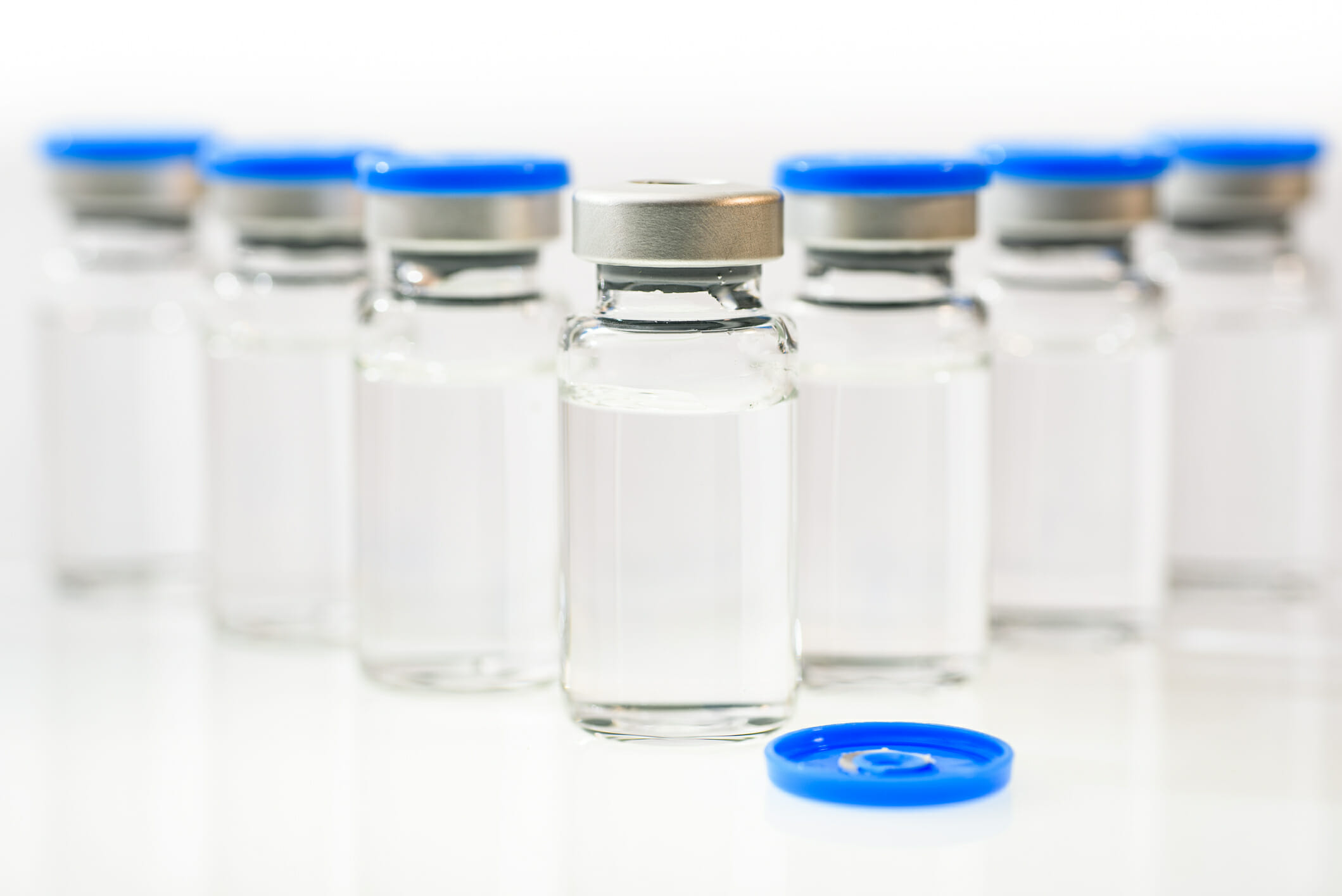 Clear vials of medicine with blue caps