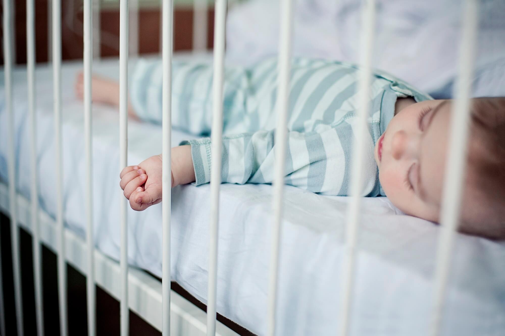 An infant sleeping in a crib.