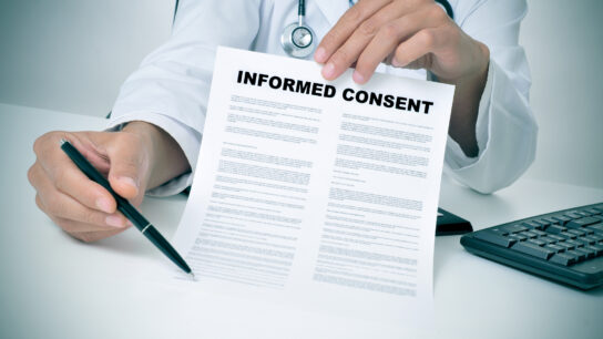 a doctor in his office showing an informed consent document and pointing with a pen where the patient must to sign