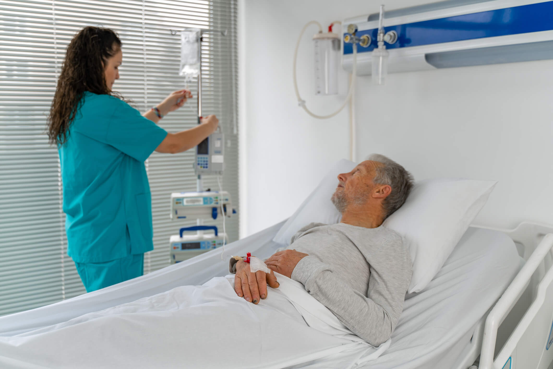 Male patient on hospital bed while doctor checks IV.