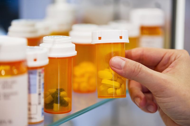 A woman reaching for a prescription bottle in a medicine cabinet