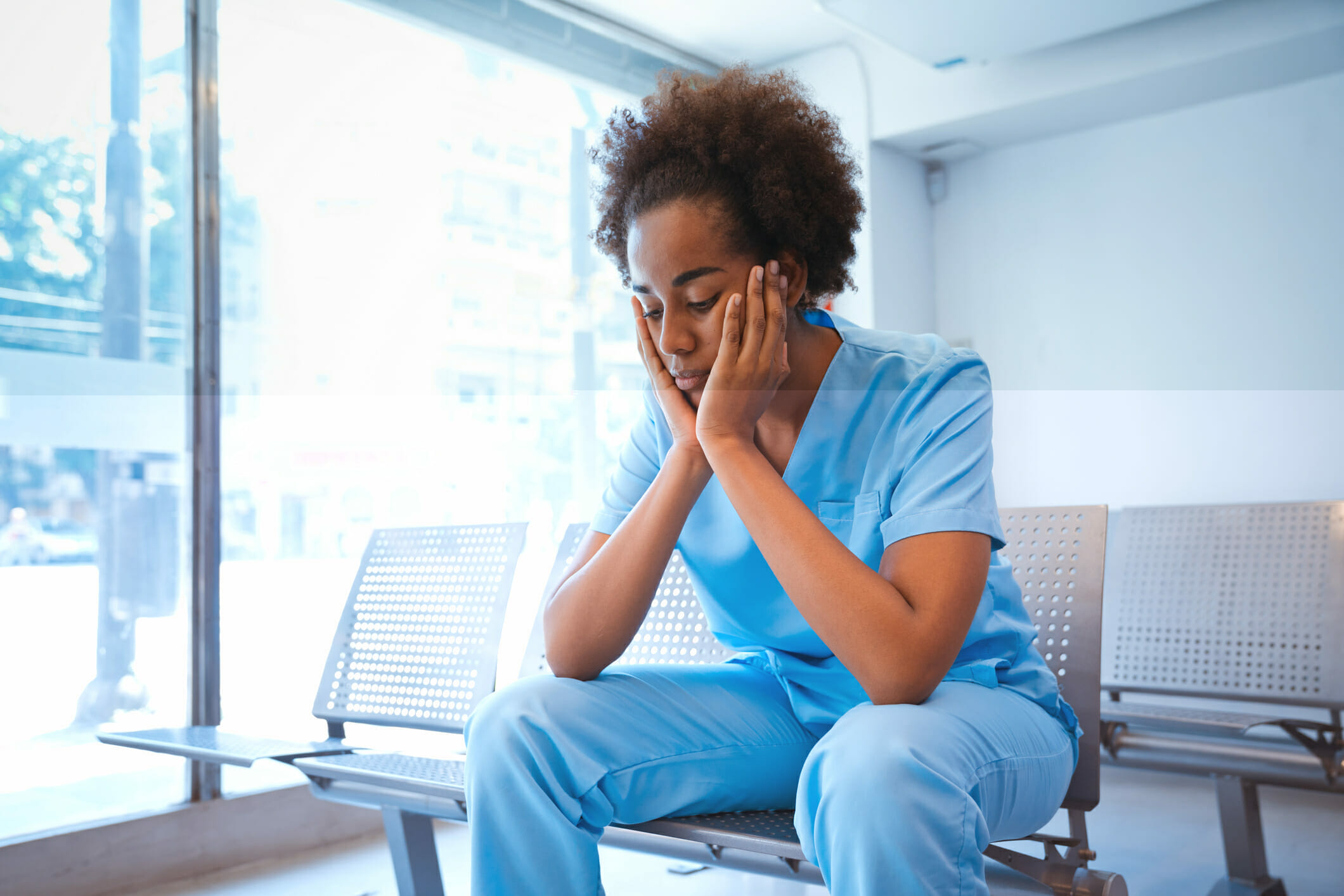 Nurse sitting in hospital with face in hands