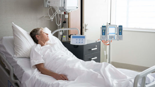 Older female patient in hospital bed.