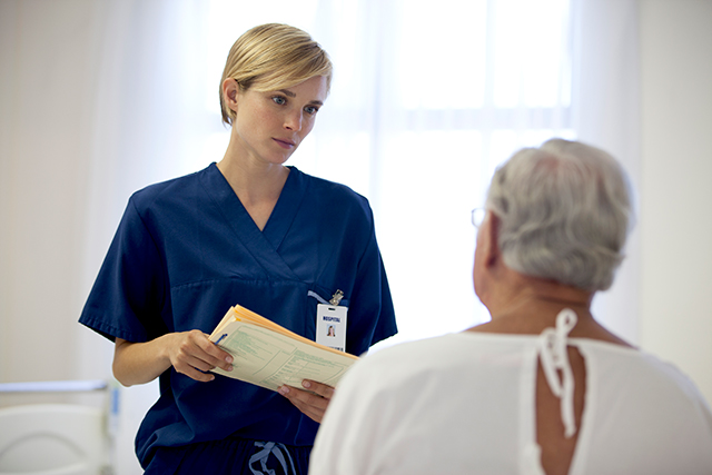 A nurse confers with a patient.