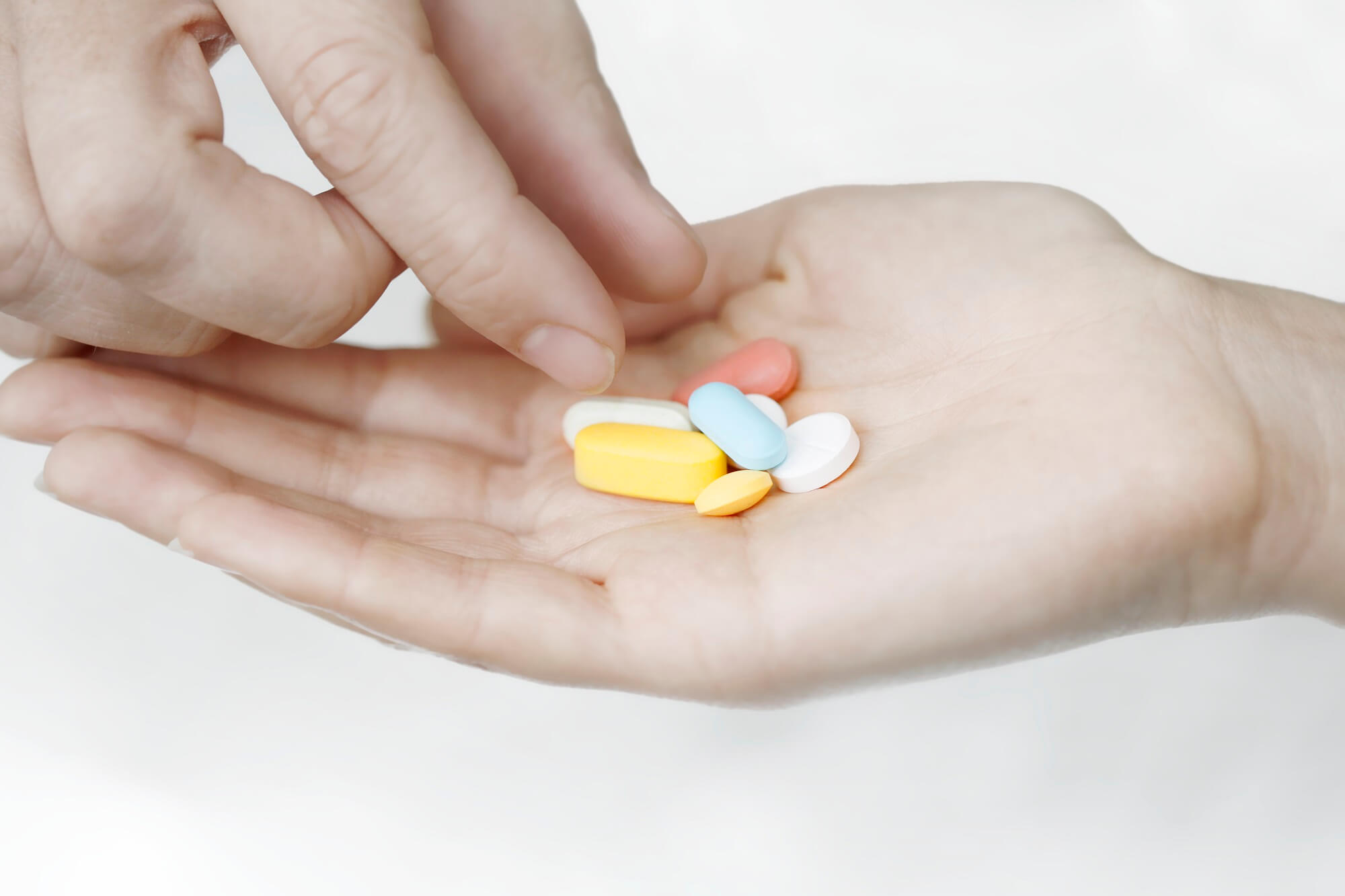 Closeup of several multicolored pills in the palm of someone's hand.