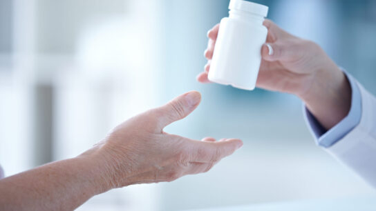 Female pharmacist giving a tablet bottle to patient