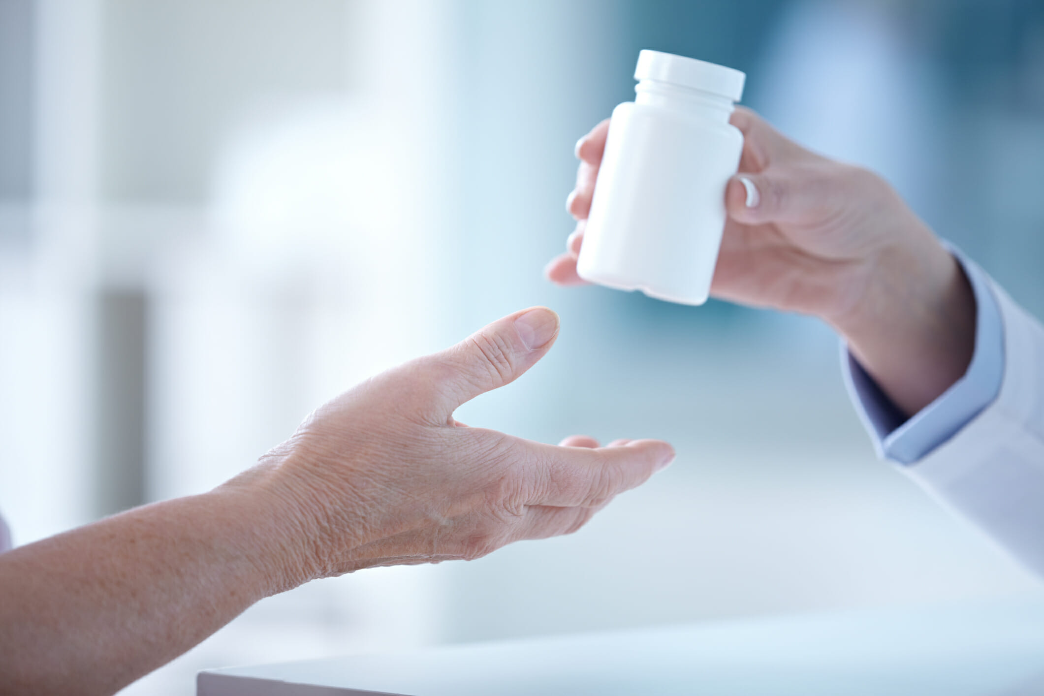 Female pharmacist giving a tablet bottle to patient