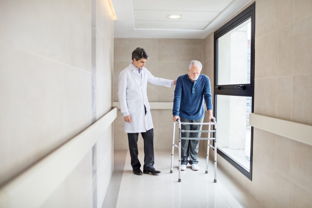 Patient with walker being helped by health care worker