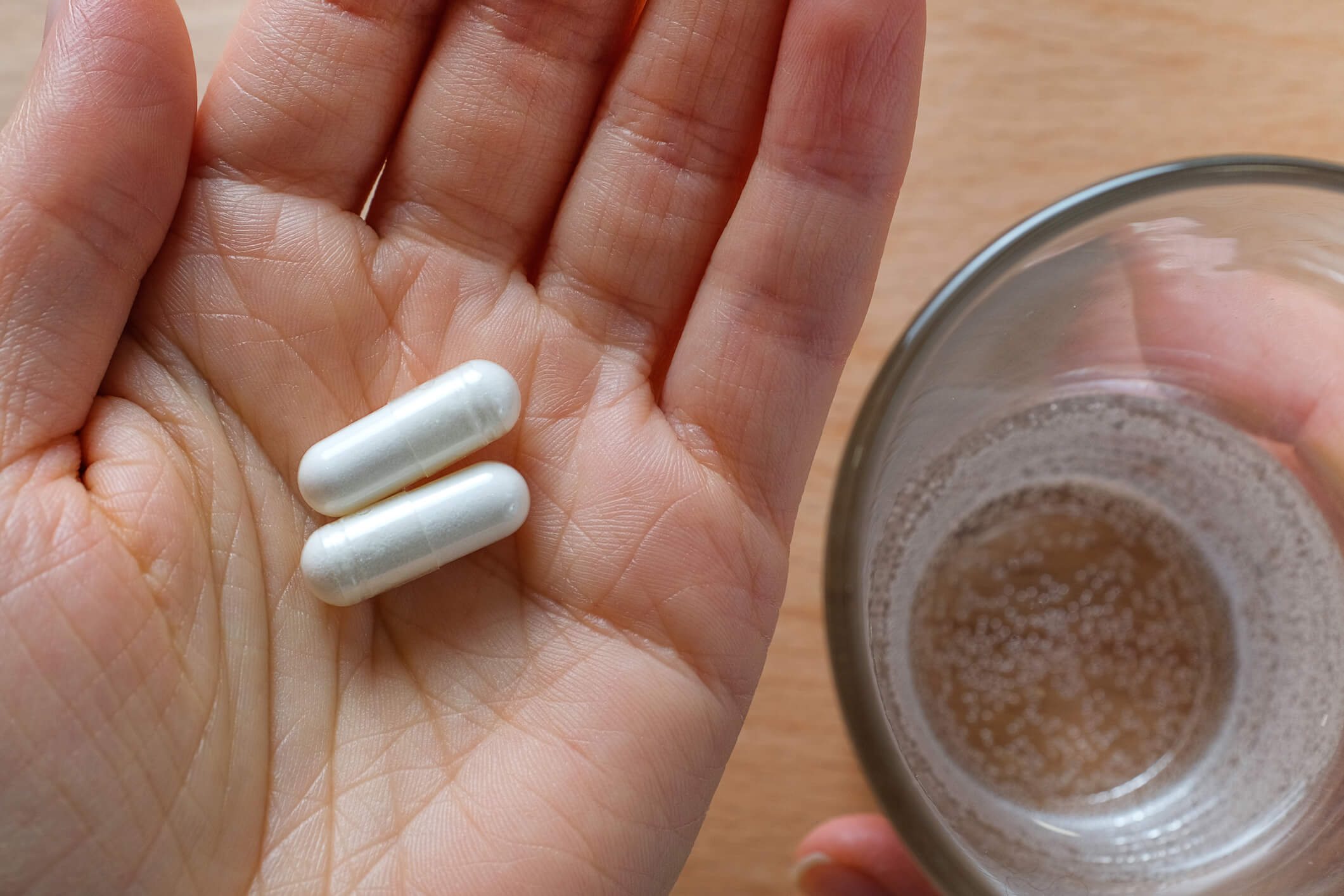 Image of patient holding white capsules.